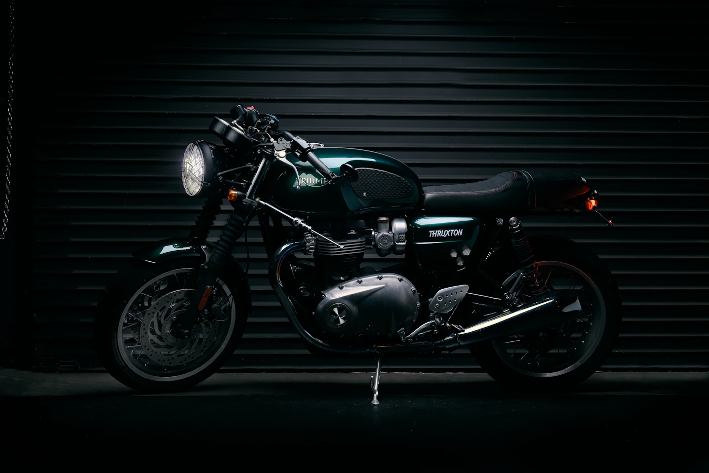 Matte black brat style motorcycle photographed against a black backdrop