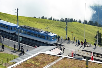 A traveler consulting a map beside a scenic Swiss train station surrounded by alpine scenery.