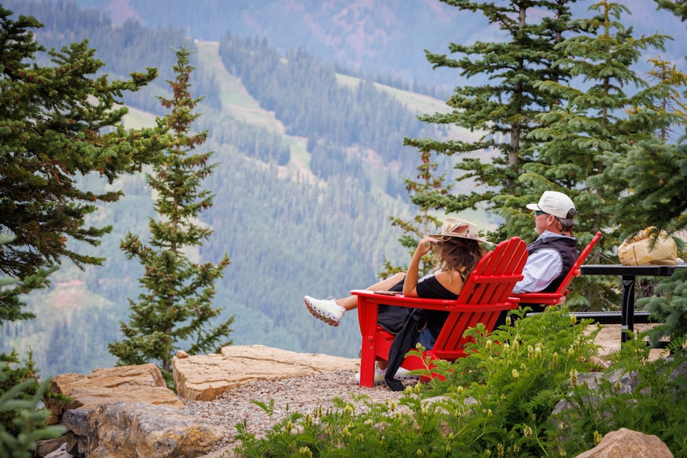 a man and a woman sitting on a bench overlooking a mountain range