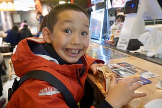 A child smiling shyly while receiving a warm meal in a community center.