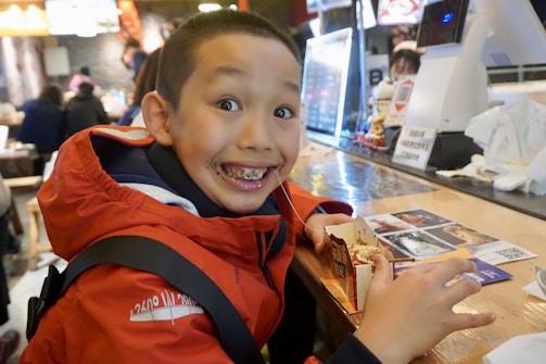 A child smiling shyly while receiving a warm meal in a community center.