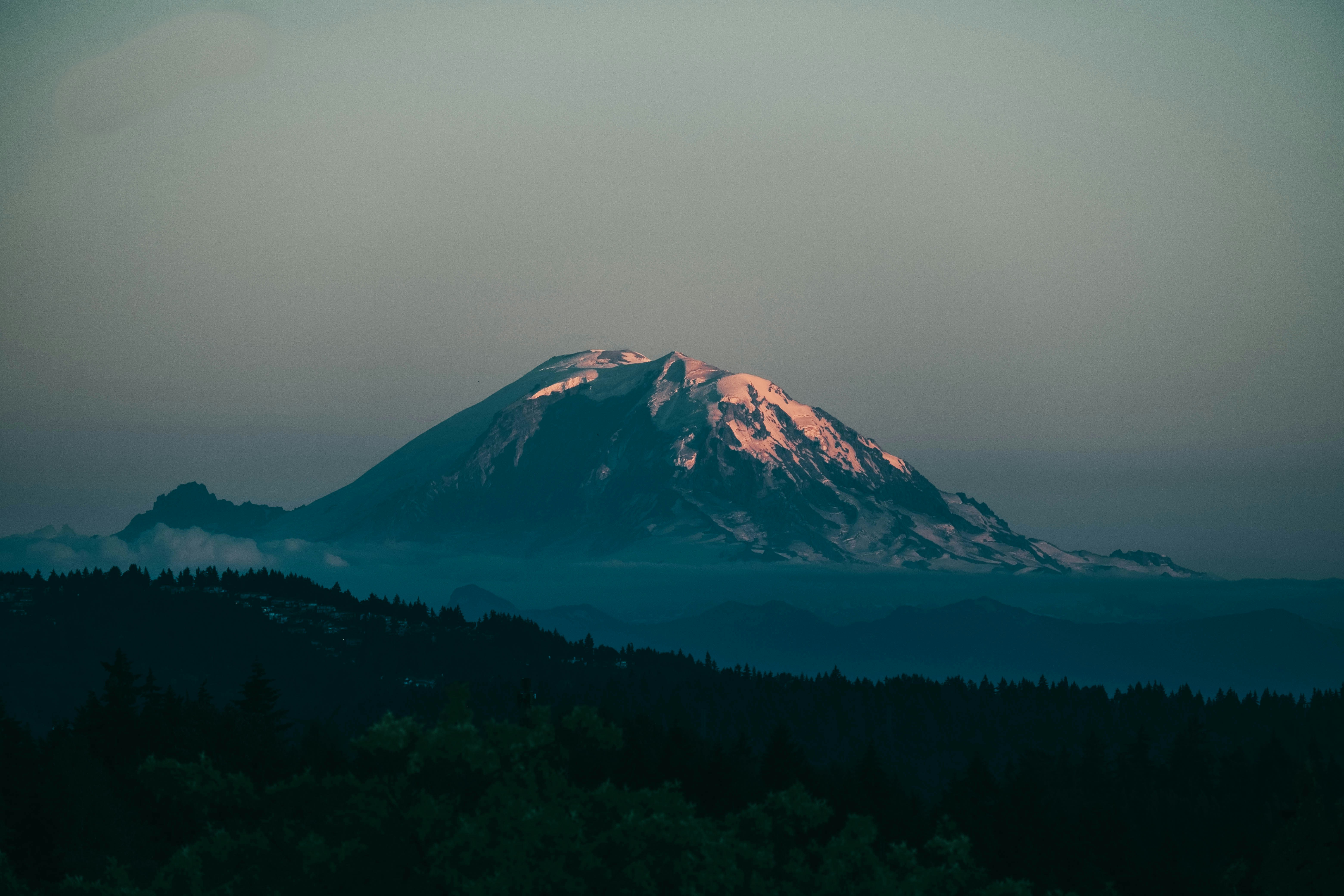 a snowy mountain with trees below