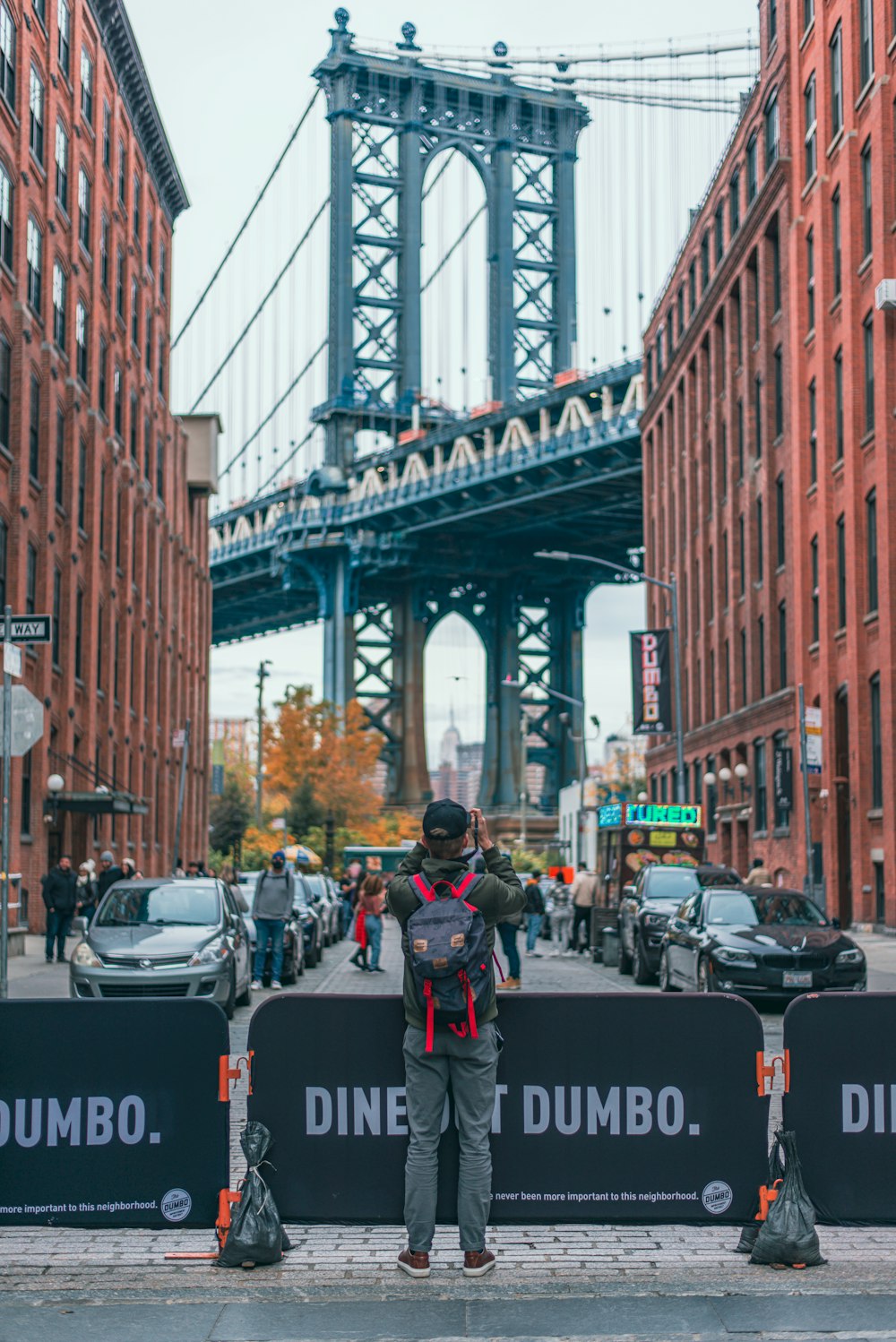 a person standing on a sidewalk in front of a bridge