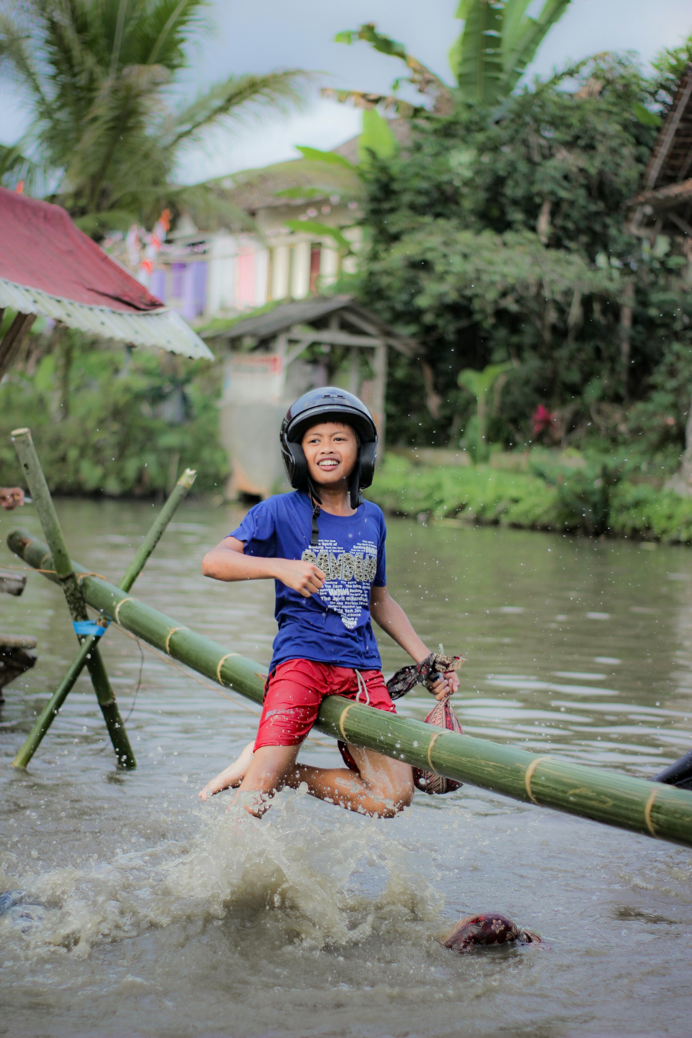 seorang anak berhelm memegang tongkat di sungai