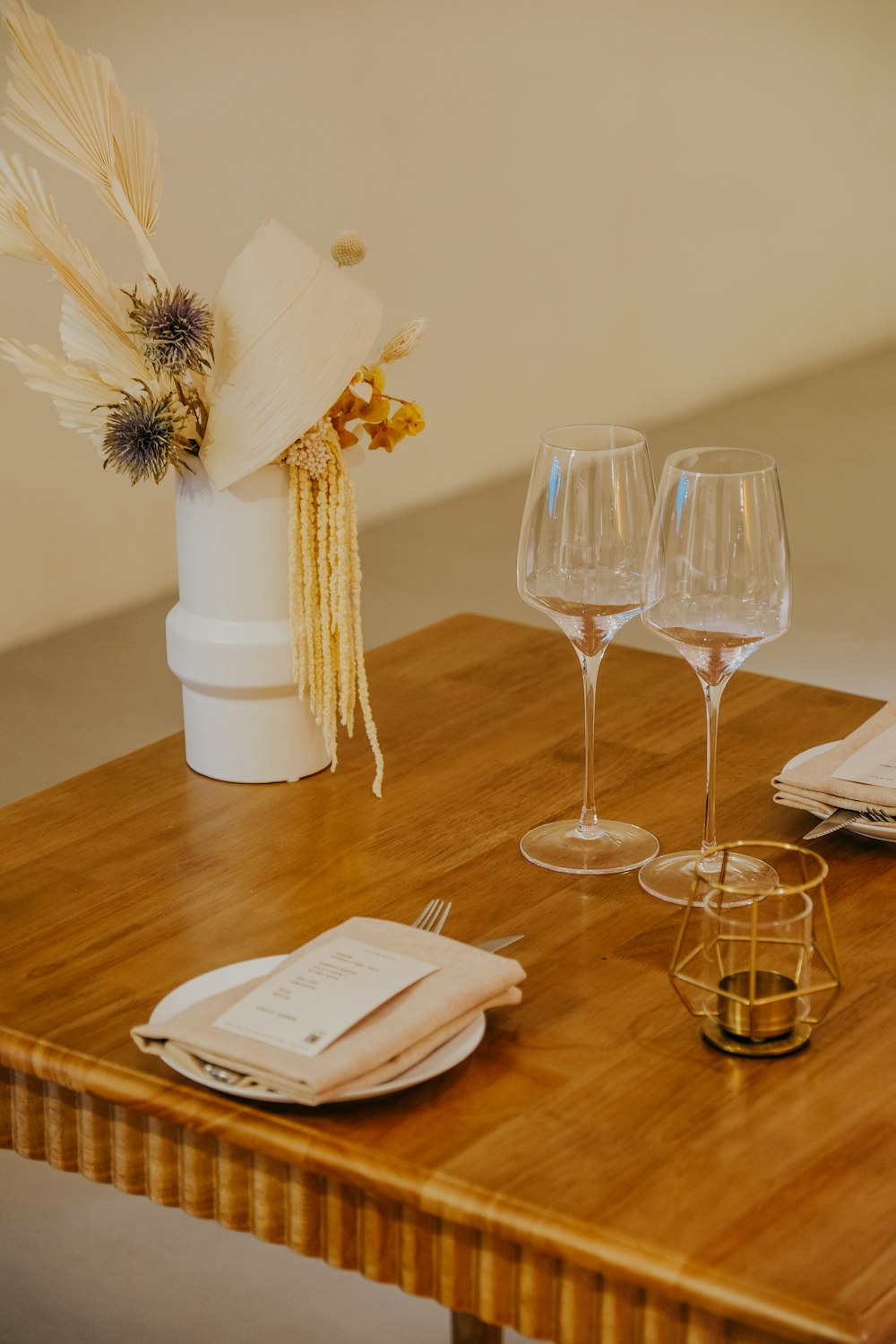 a vase with flowers and glasses on a table