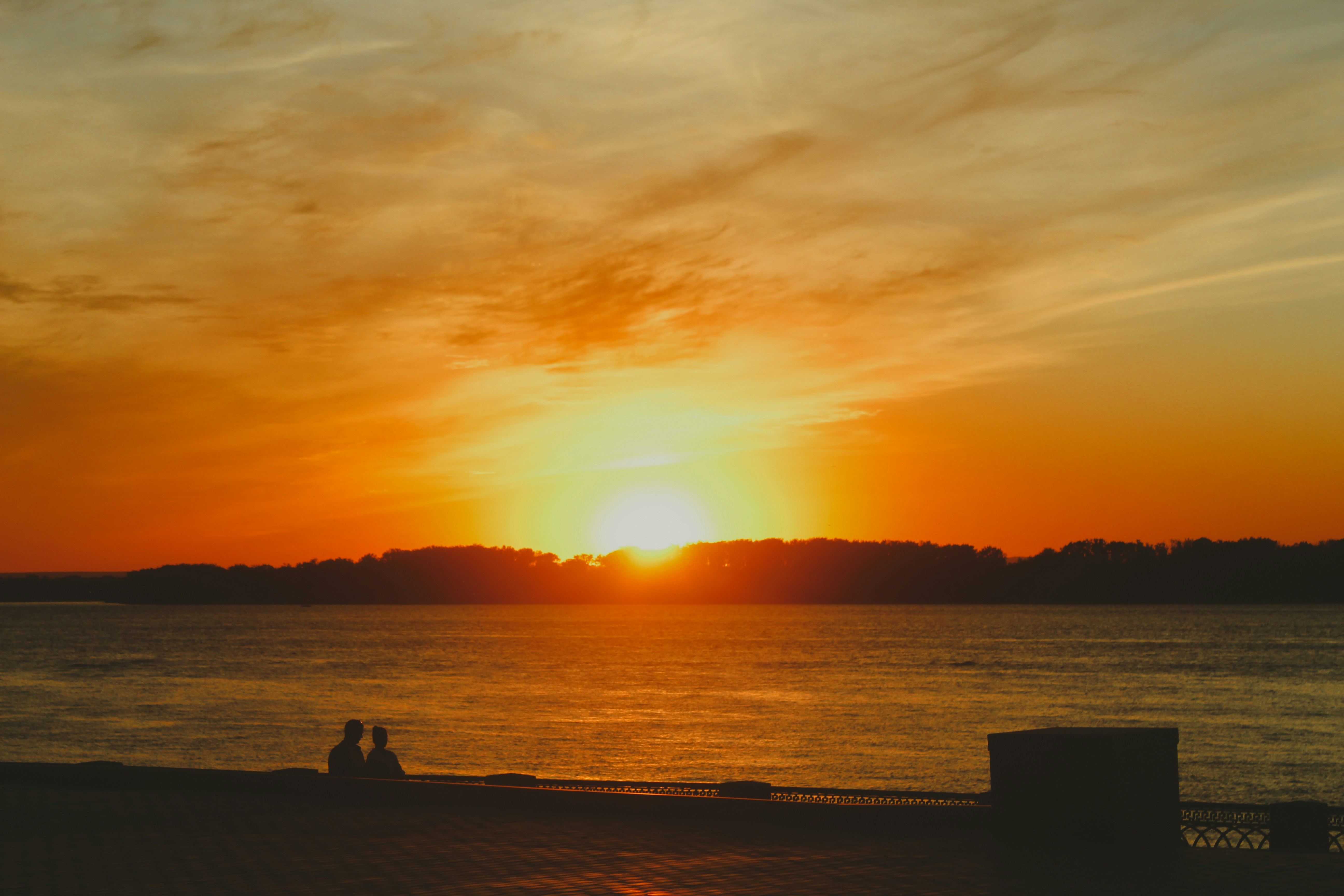 a person sitting on a dock looking at the sunset