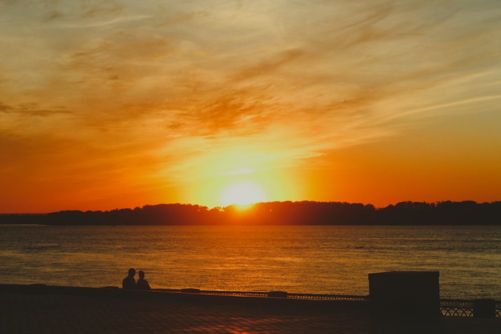 a person sitting on a dock looking at the sunset