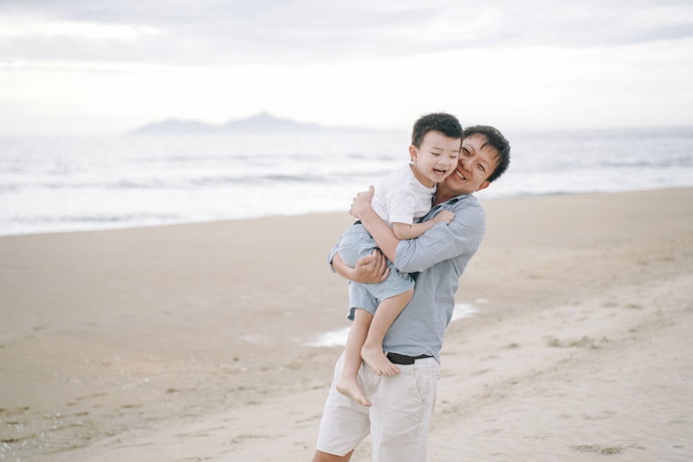 a person carrying a baby on a beach