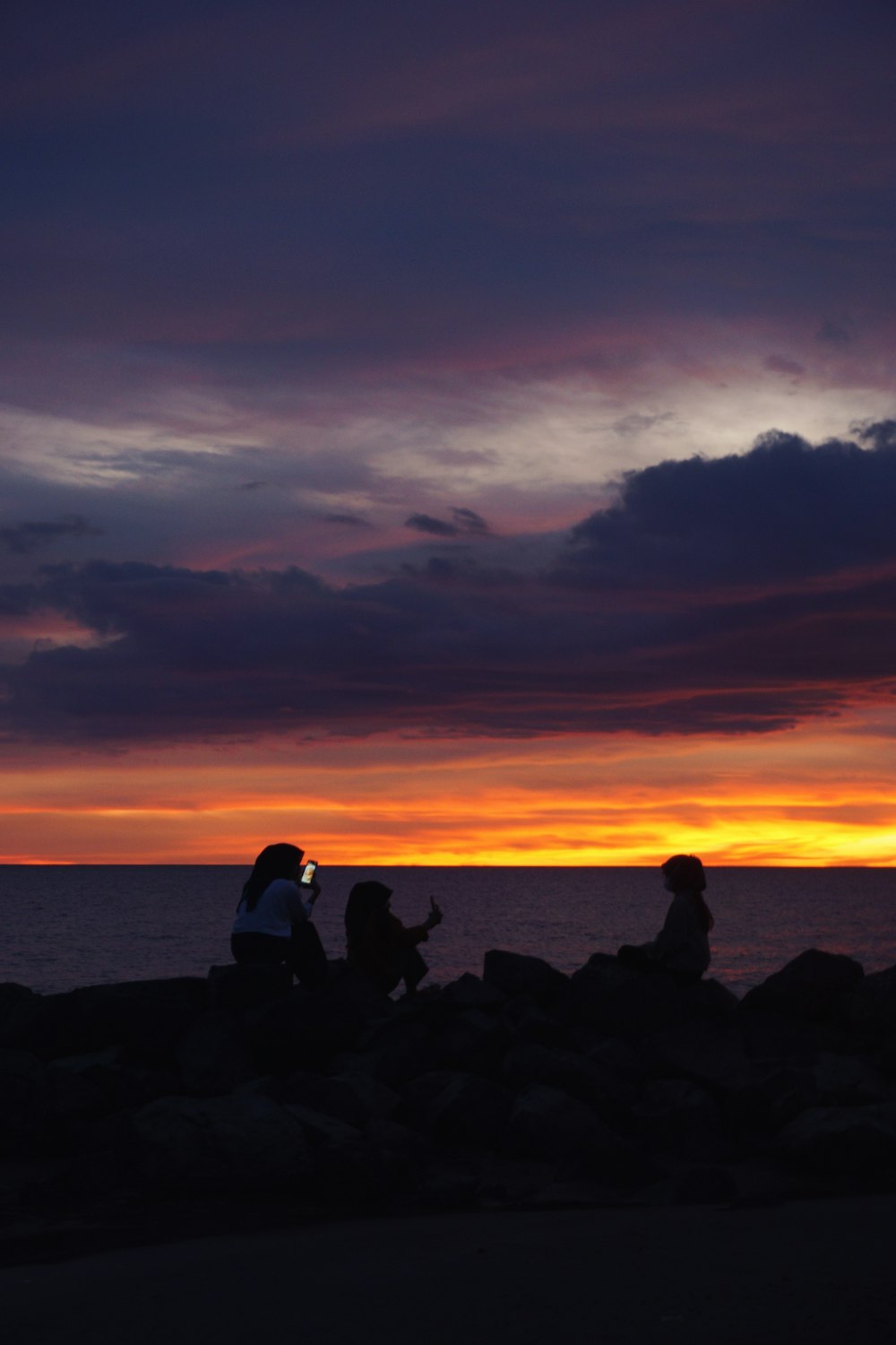 people sitting on rocks at sunset