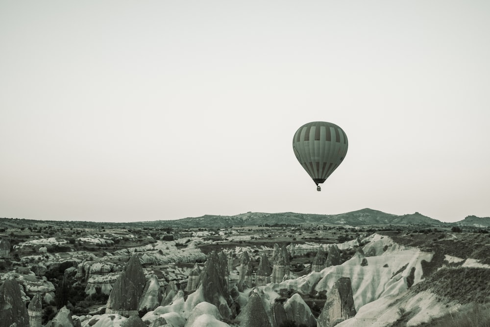 a hot air balloon flying over a rocky landscape
