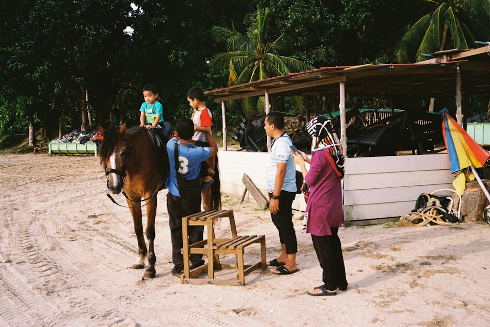 a group of people stand around a horse