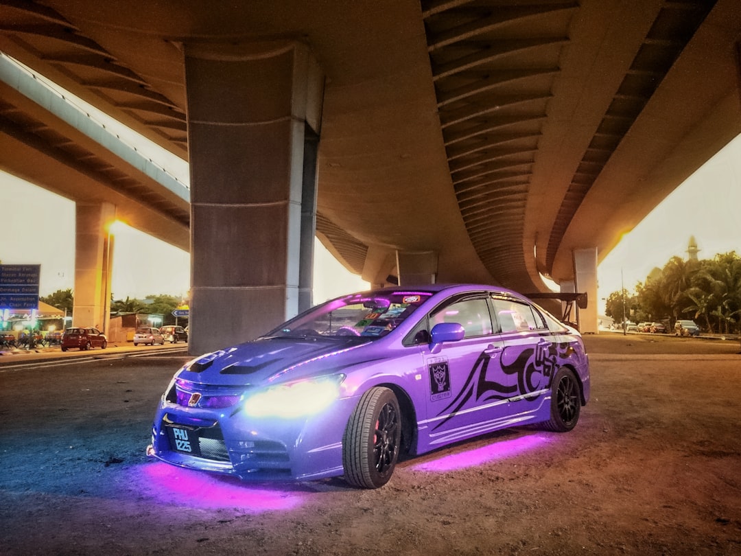 a purple car parked under a bridge,