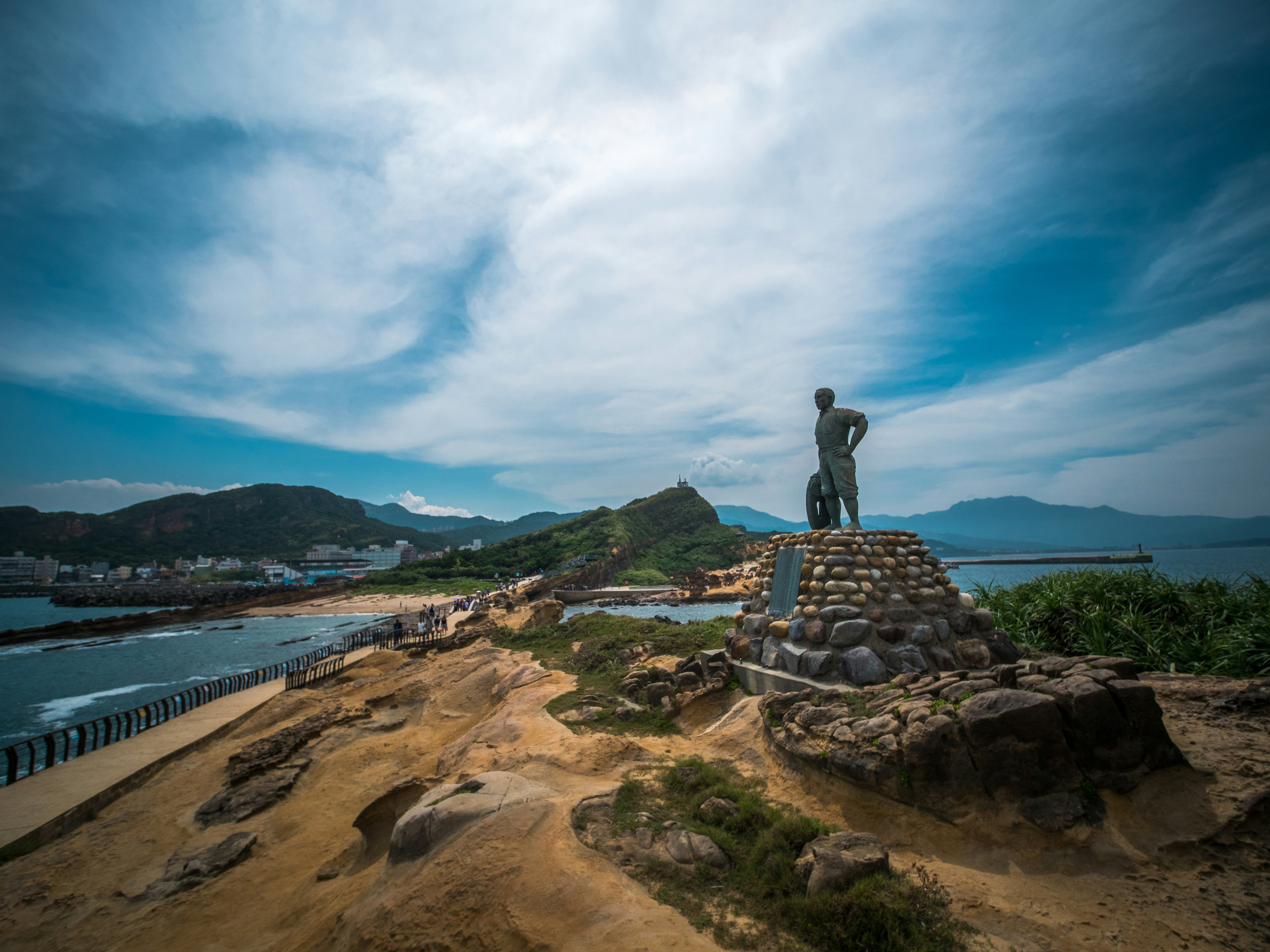 a statue on a rock by a body of water