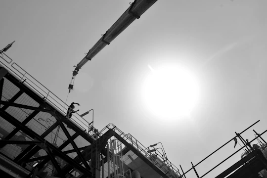 A construction worker using a tablet on site to photograph project progress under bright daylight.