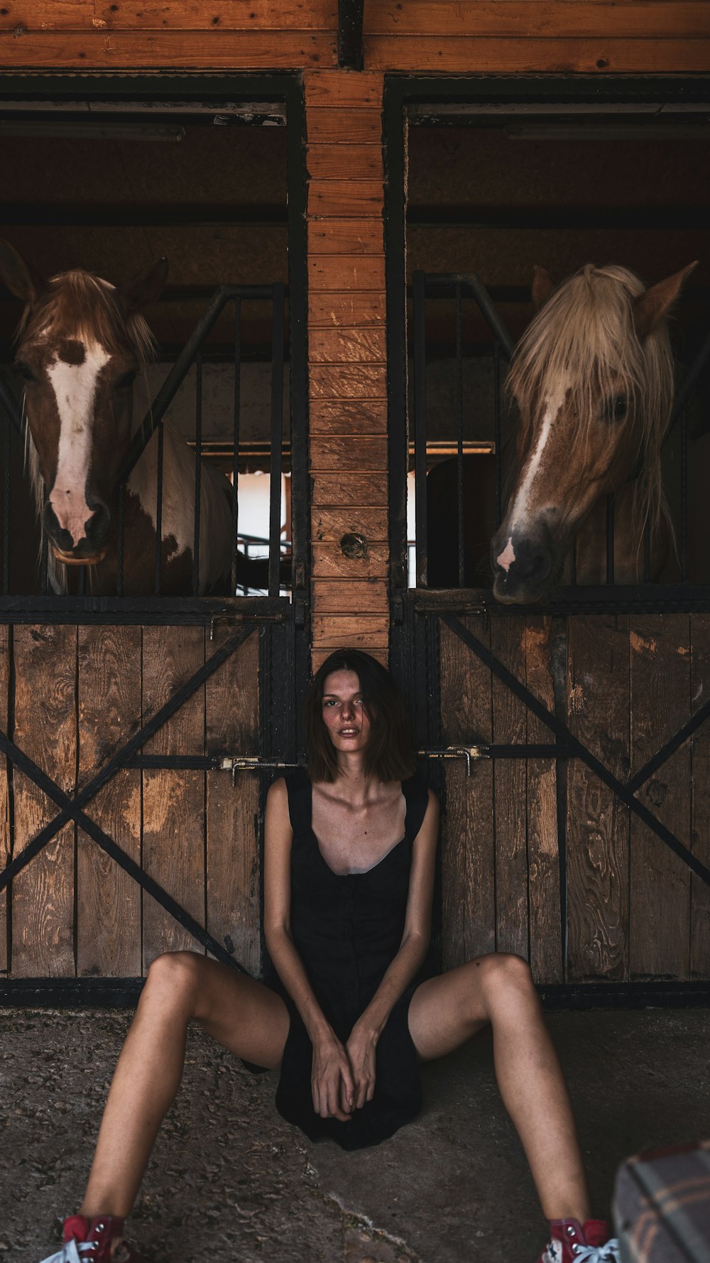 a person sitting in a barn with a horse in the background