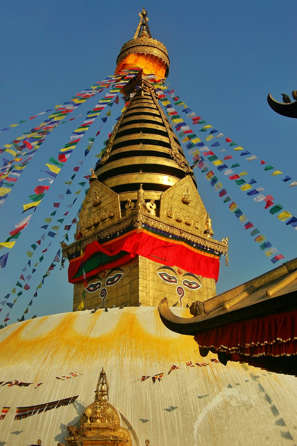 a colorful building with a gold roof with Swayambhunath in the background