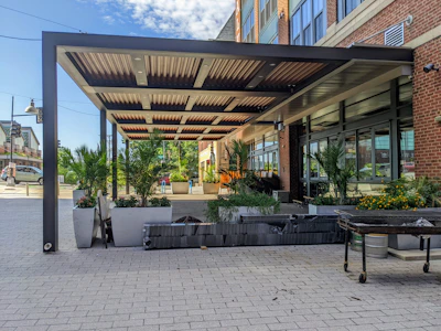 Modern outdoor patio surrounded by a combination of potted plants and manicured shrubs.