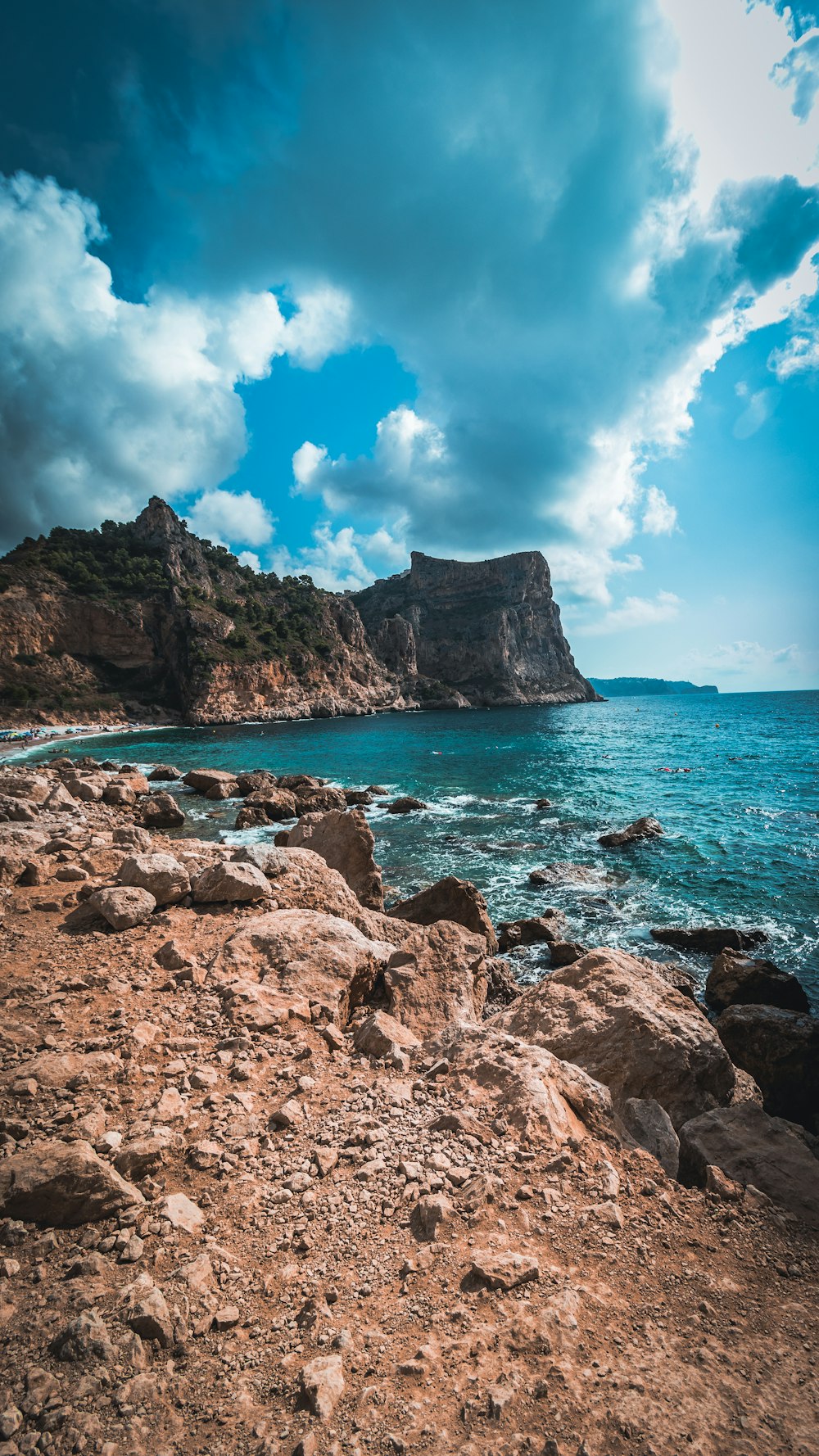 a rocky beach with a large body of water in the background