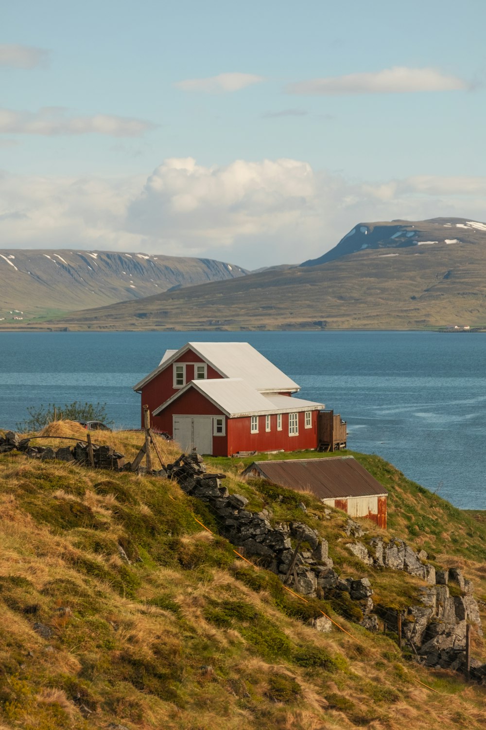 a red house on a hill by the water