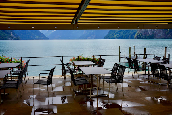 Outdoor terrace with tables overlooking Zugersee and surrounding mountains.