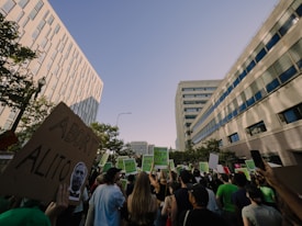 A crowd of people gathered between tall buildings, holding signs with slogans such as 'Abort Alito' and 'Overturn Roe? Hell No!' in a protest. The scene captures a mixture of emotions as people advocate and express their views.