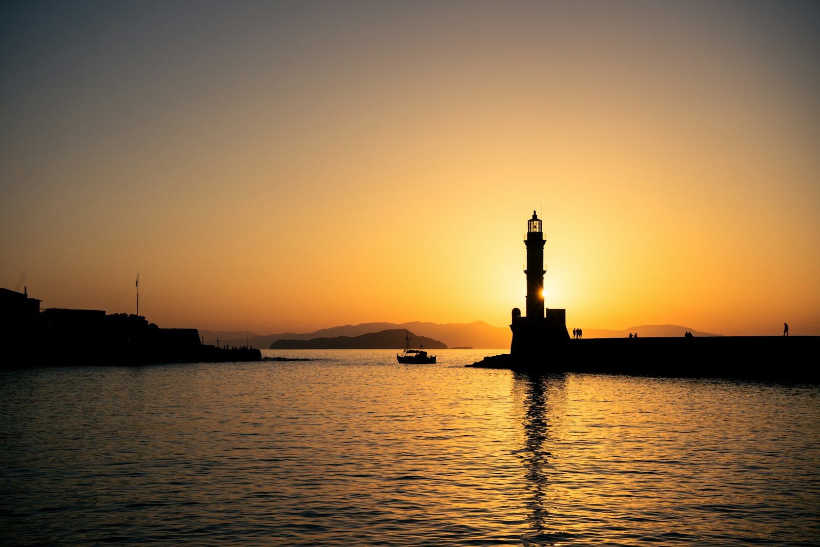 The Venetian lighthouse at the entrance to Chania's old harbor, silhouetted at sunset