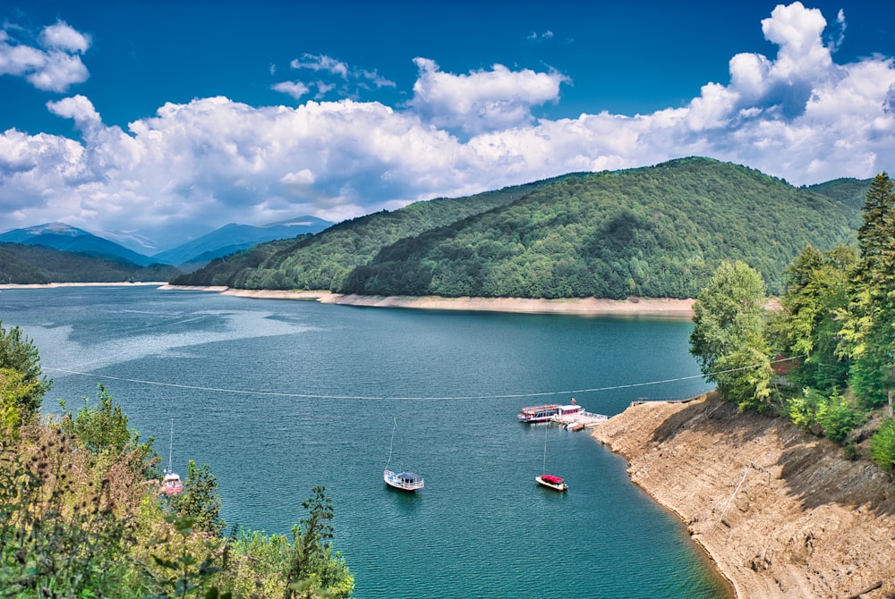 a body of water with boats in it and hills in the back