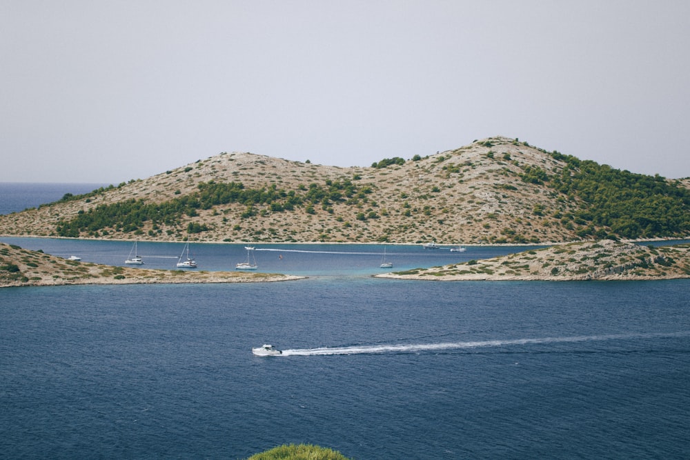 a body of water with boats in it and a hill in the background