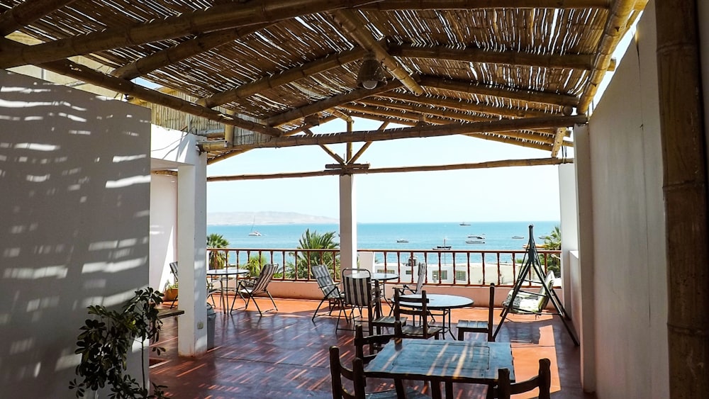 a patio with tables and chairs and a body of water in the background