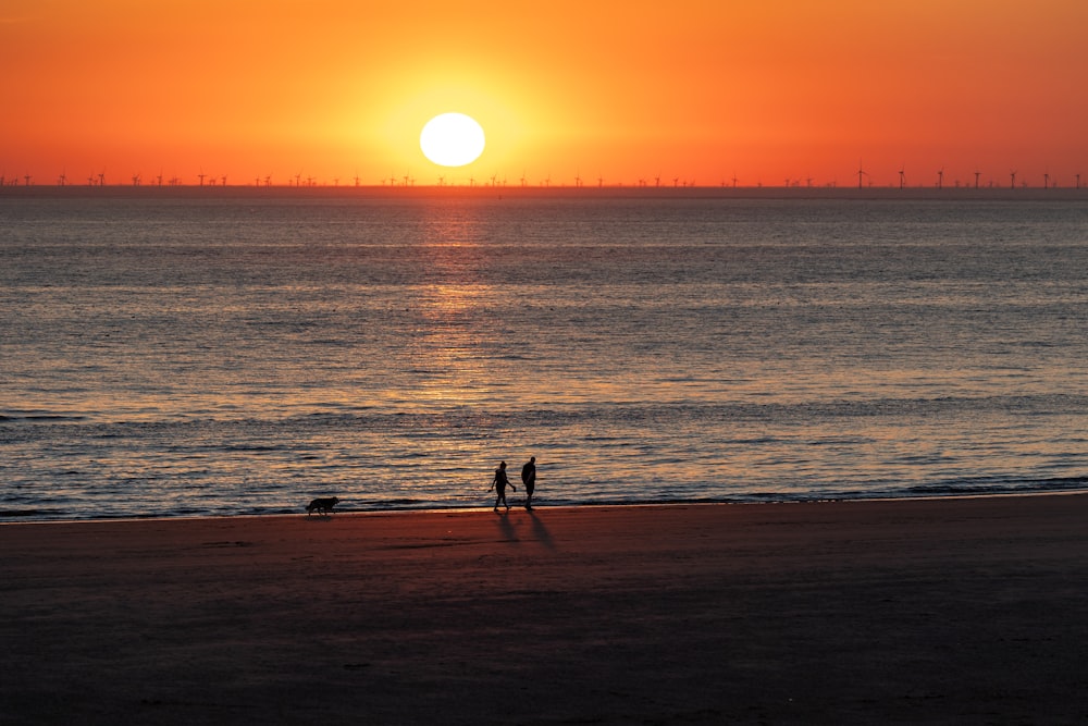 un par de personas en una playa con Sunset Beach al fondo