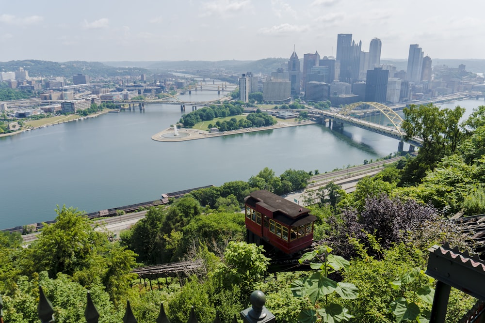 a red trolley car on Duquesne Incline over a river with a city in the background