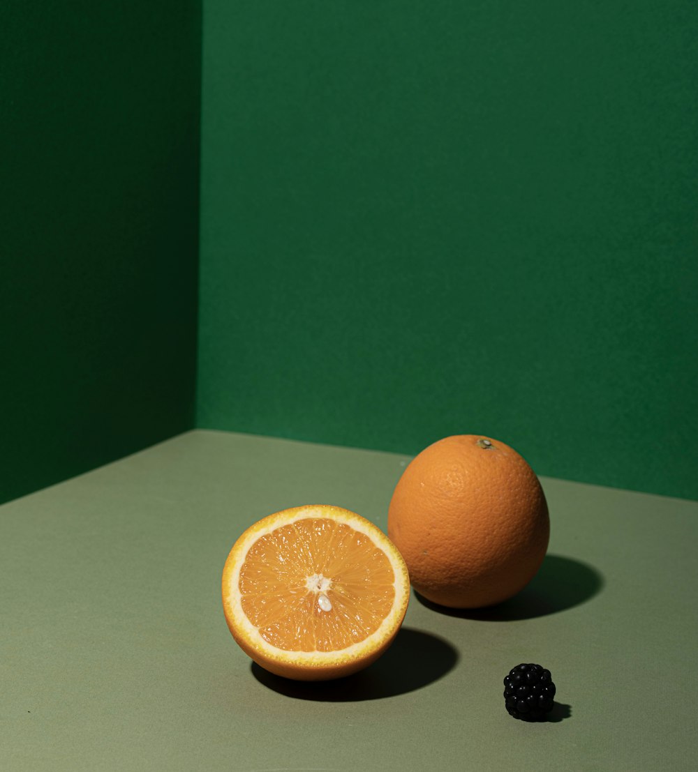 a couple oranges and a black berry on a white surface
