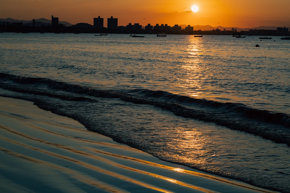 a beach with boats and a sunset