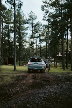 An SUV parked on a gravel path with trees in the background, ready for a weekend trip.