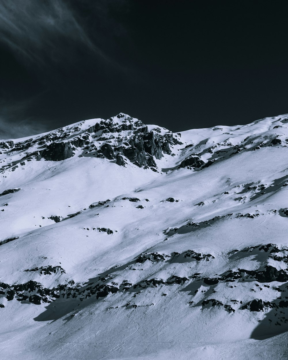 a snowy mountain with a dark sky