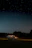 A car interior glowing softly with star roof lights under a clear night sky.
