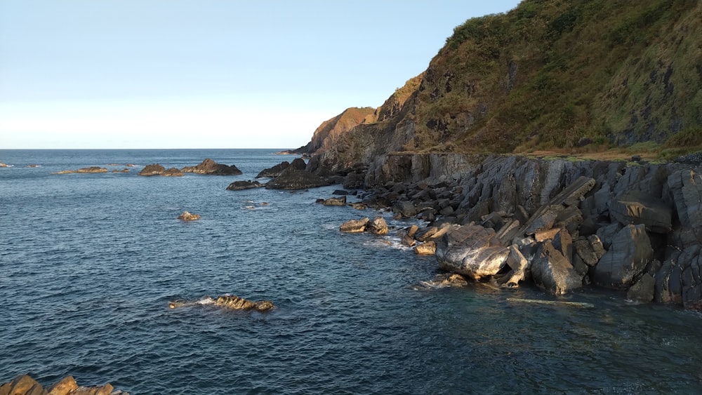 a rocky beach with a hill in the background