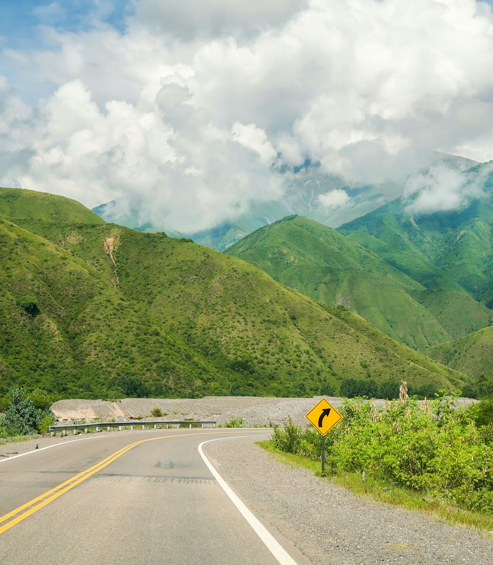 a road with a sign on it and a mountain in the background