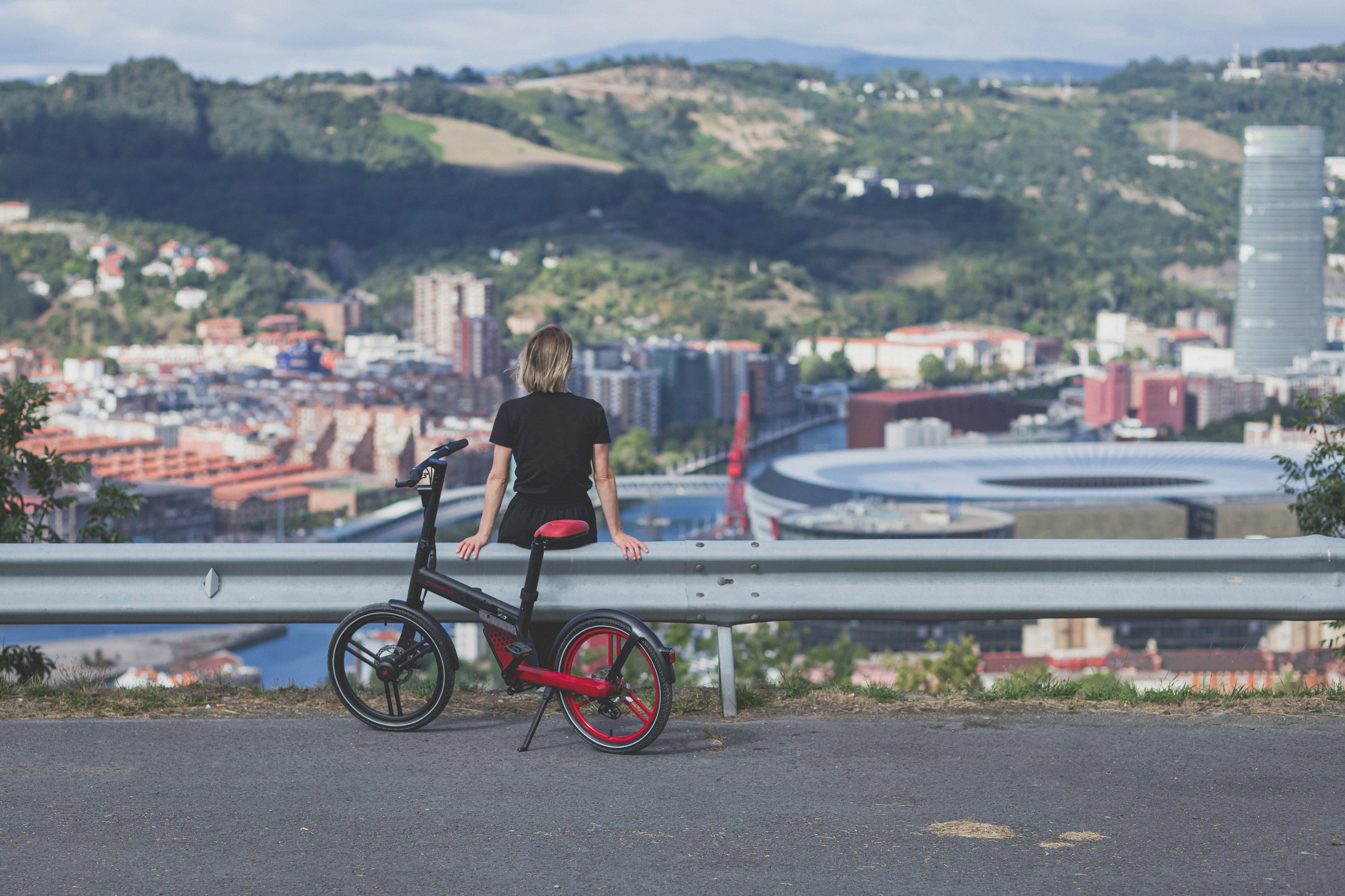 a man riding a bicycle on a bridge over a city