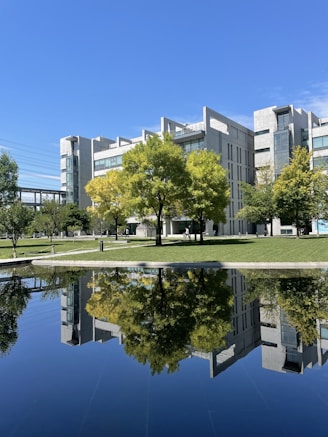 a building with trees and grass by a body of water