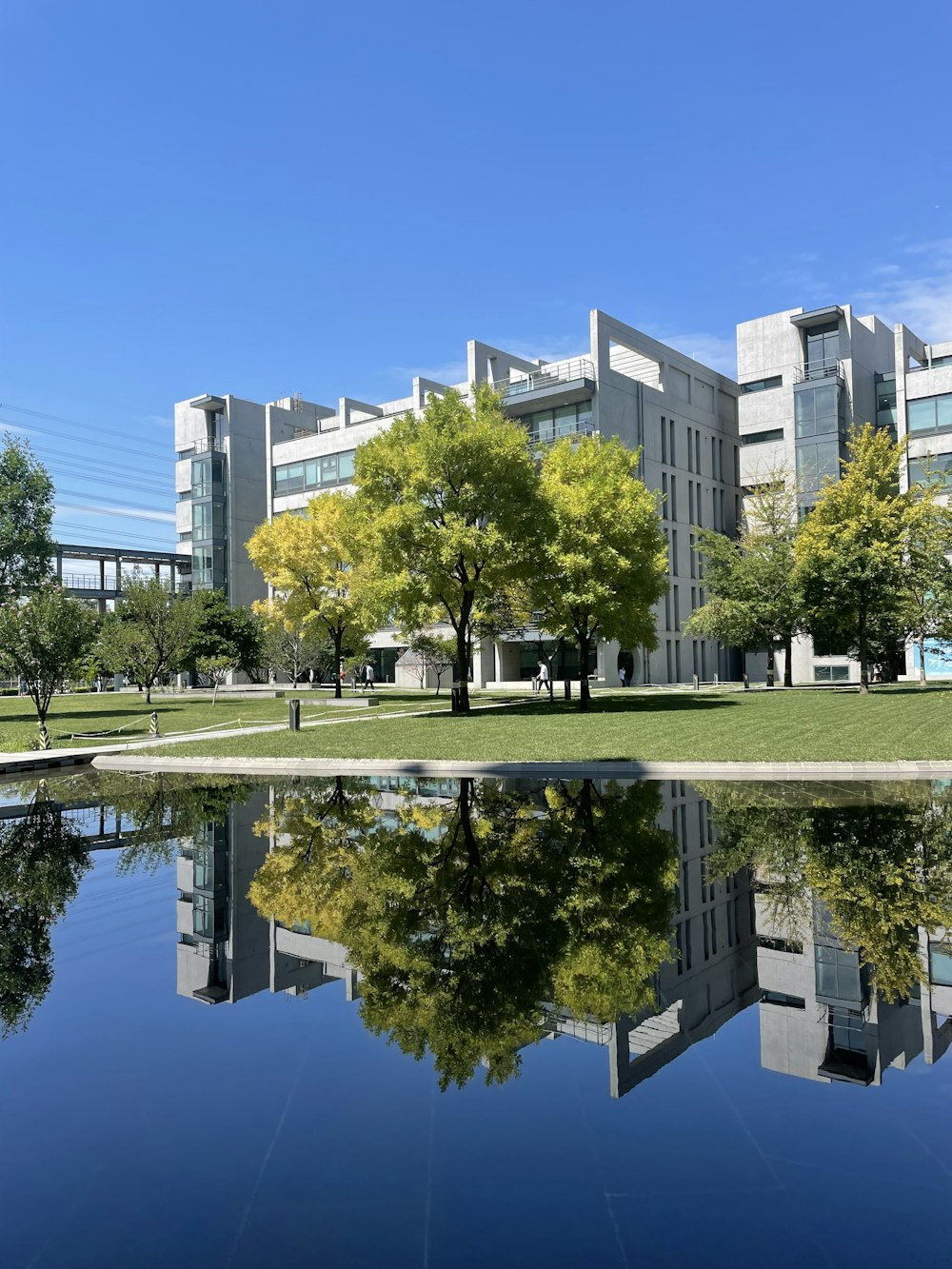 a building with trees and grass by a body of water