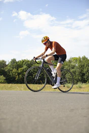A cyclist in an orange jersey and helmet riding a road bike