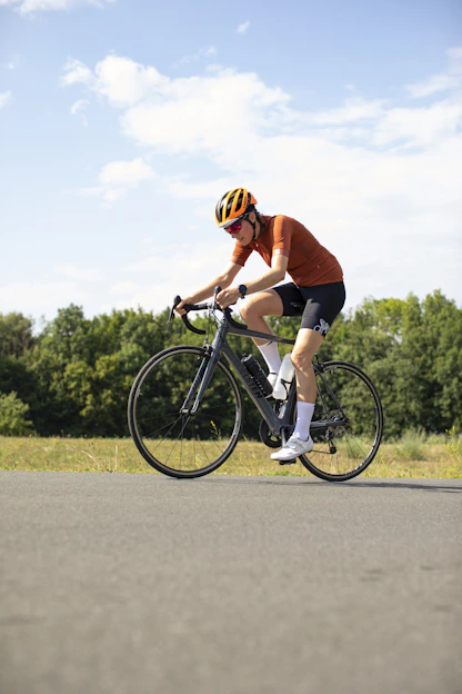 A cyclist in an orange jersey and helmet riding a road bike