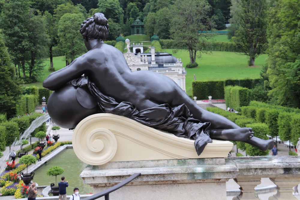 a statue of a person sitting on a fountain in a park