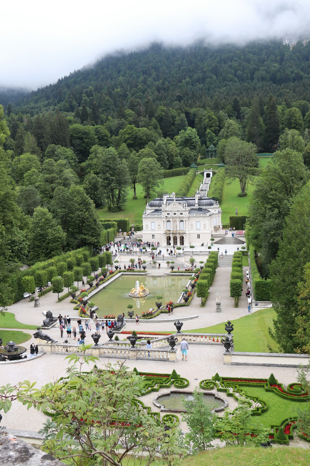 ein großes weißes Gebäude mit einem Pool davor und Bäumen drumherum