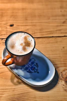 A sleek ceramic cup with a matte finish in soft pastel blue sitting on a wooden table.