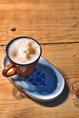 A steaming cup of traditional South Indian filter coffee resting on a handcrafted ceramic saucer.