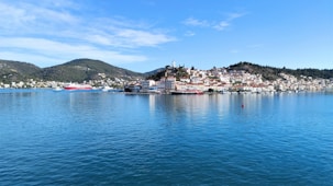 a body of water with buildings and hills in the background
