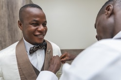 a man in a tuxedo smiling at another man in a tuxedo