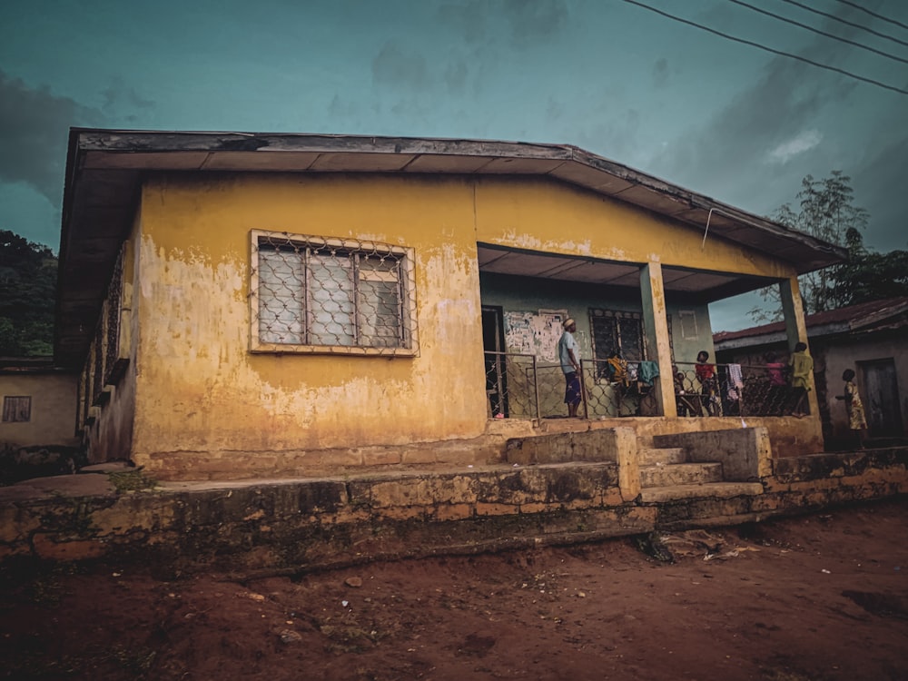 a yellow house with a few people standing outside